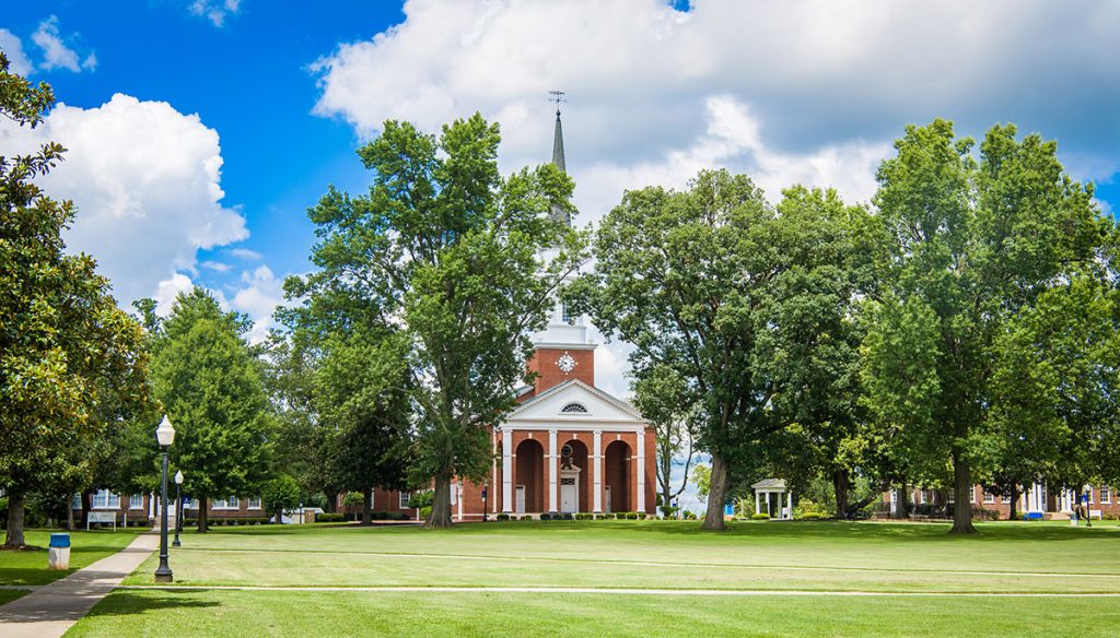 Picture of Bennett College Campus featuring grassy lawn against backdrop of trees and a brick building