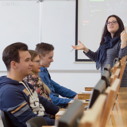 Instructor using AI in higher education, engaging with college students during class..