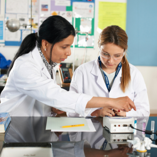 Image of college instructor working with a female student in a lab setting demonstrating career guidance through working on a piece of equipment.