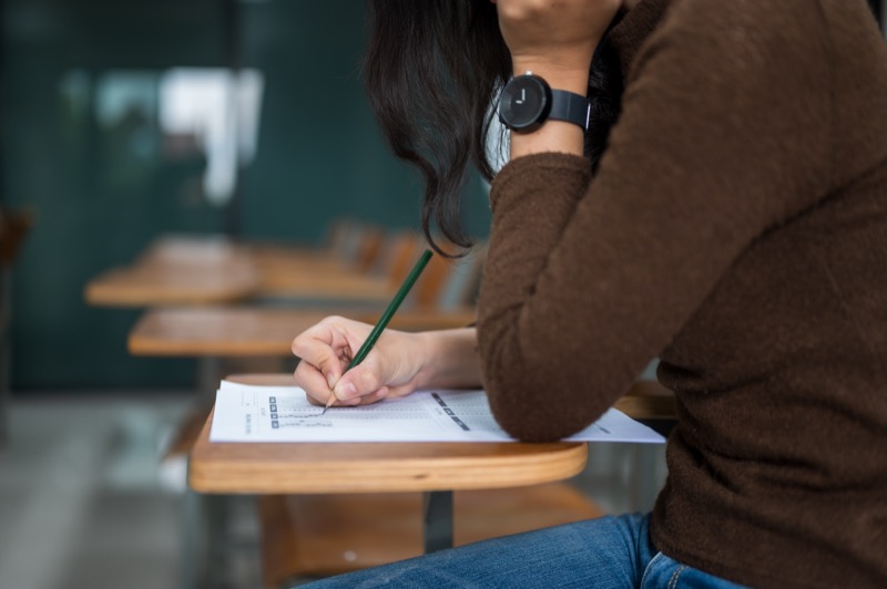 A student focuses intently while writing notes, showing the impact of great teaching in encouraging active learning and concentration