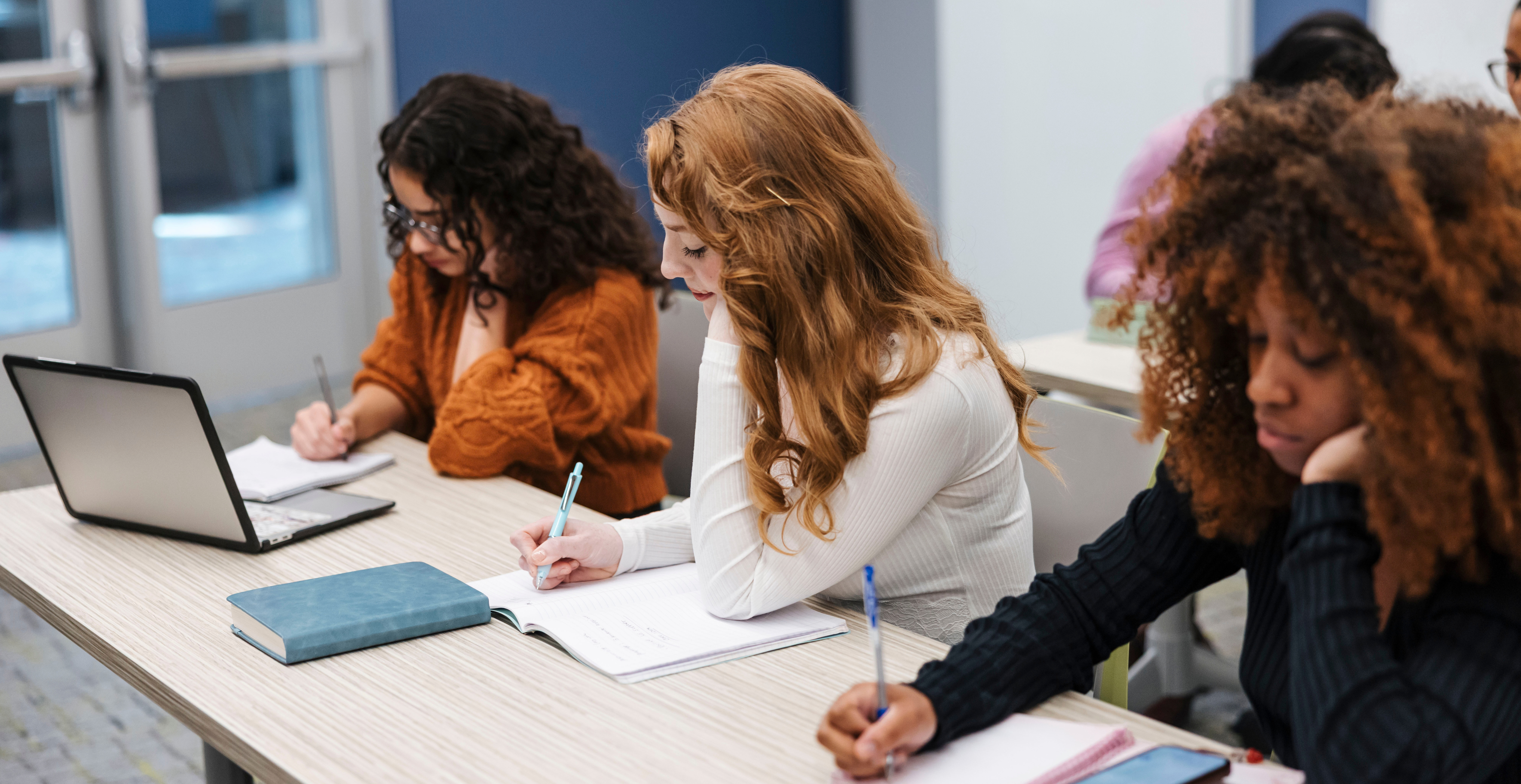 three students studying in a college classroom